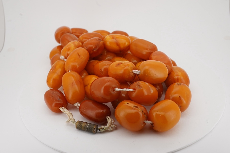 A single strand oval and barrel shaped amber bead necklace, 90cm, gross weight 102 grams. Condition - poor to fair